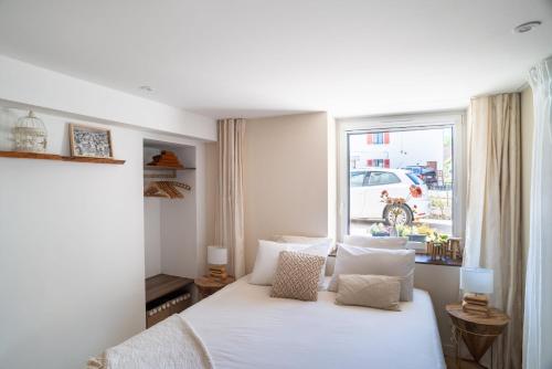 1 dormitorio con cama blanca y ventana en Charmant Studio paisible dans le Centre du Village en Échenevex