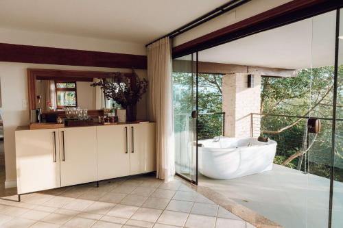 a bathroom with a tub and a large window at Naatooh Guest Houses in Florianópolis