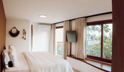 a bedroom with a bed and a large window at Naatooh Guest Houses in Florianópolis