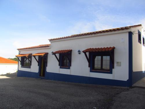 a white and blue building with black windows at Golf & Surf Holiday House in Casal da Lagoa Seca