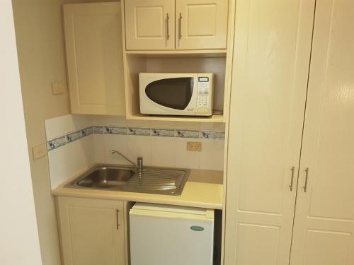 a small kitchen with a sink and a microwave at Acacia Motel in Griffith