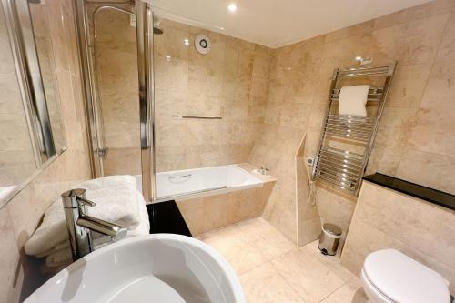 a bathroom with a tub and a toilet and a shower at Castle Bromwich Hall; Sure Hotel Collection by Best Western in Birmingham