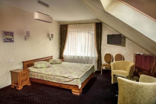 a bedroom with a bed and a window and chairs at Kambarių nuoma Žasliuose in Žasliai