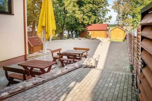 a patio with two wooden tables and a yellow umbrella at Kambarių nuoma Žasliuose in Žasliai