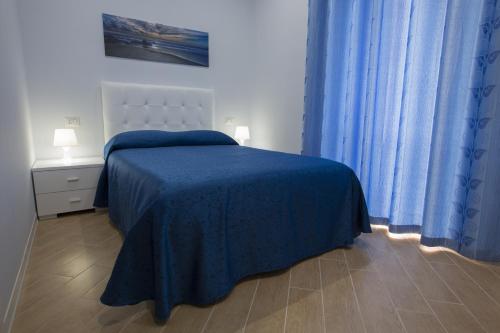 una camera da letto con un letto con una coperta blu e tende blu di Residenza Duomo ad Avezzano