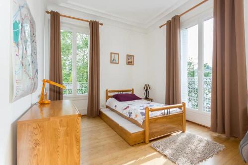 een slaapkamer met een bed en een groot raam bij J'aime Paris 1st in Boulogne-Billancourt