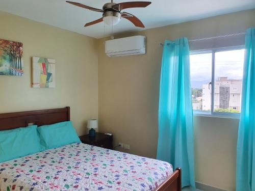 a bedroom with a bed with a ceiling fan and a window at Verano 2019 in Santiago de los Caballeros