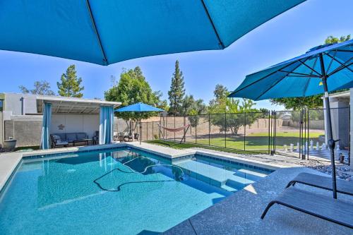 a swimming pool with an umbrella and two chairs and a swing at 1 Mi to Dobson Ranch Modern Escape with Gazebo! in Mesa