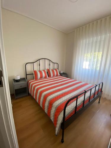a bedroom with a bed with a striped blanket and a window at Boa Passagem in Peso da Régua