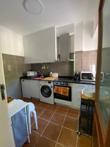 a kitchen with white cabinets and a washer at Boa Passagem in Peso da Régua