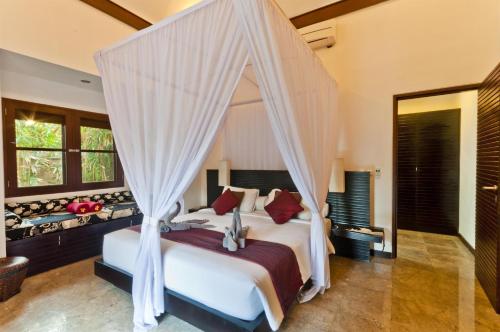 1 dormitorio con 1 cama con dosel en Villa Blubambu, en Seminyak