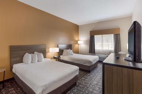 a hotel room with two beds and a flat screen tv at Best Western Logan Inn in Chapmanville