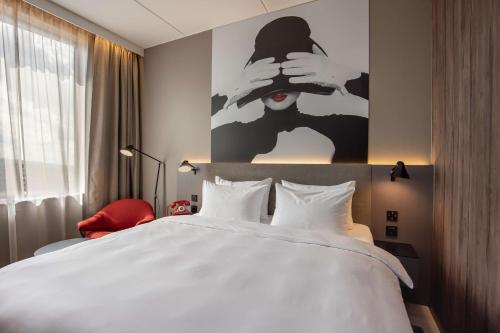 a bedroom with a large white bed and a red chair at Radisson RED Oslo Økern in Oslo