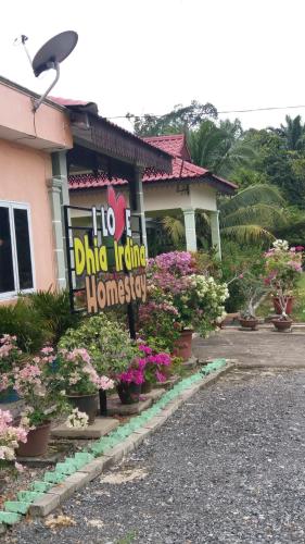 a sign in front of a house with flowers at Dhia Irdina Homestay in Paya Rewak