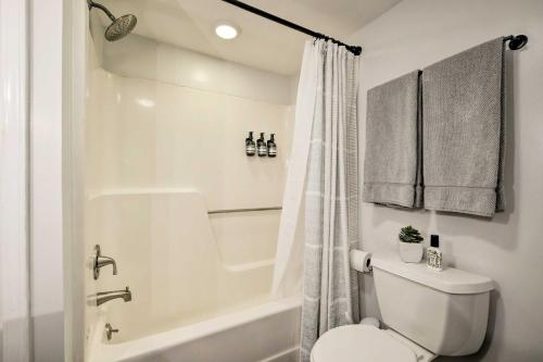 a white bathroom with a toilet and a bath tub at Dog-Friendly Raleigh Apartment about 5 Mi to Downtown! in Raleigh
