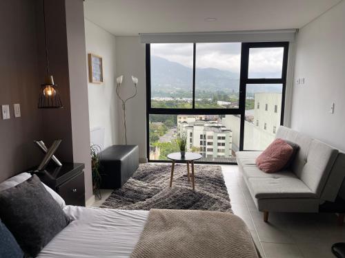 a bedroom with a bed and a couch and a large window at Hermoso Apartaestudio con excelente ubicación in Armenia