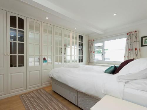a white bedroom with a large bed and a window at The Penthouse in Dartmouth