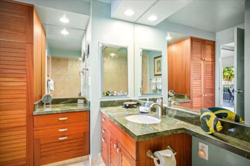 La salle de bains est pourvue d'un lavabo et d'un grand miroir. dans l'établissement Alii Villas 128, à Kailua-Kona