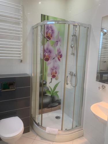 ein Bad mit einer Dusche mit einer Blume an der Wand in der Unterkunft Lotos in Rawicz