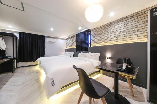 昌原市にあるMasan First Class Hotelのベッドルーム(白い大型ベッド1台、デスク付)