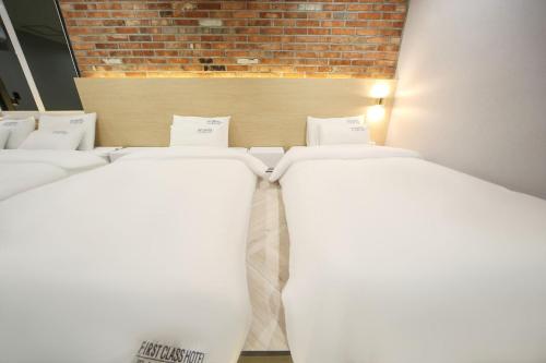 a row of white beds in a room at Masan First Class Hotel in Changwon