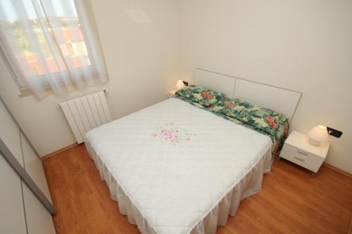 een kleine slaapkamer met een wit bed met bloemen erop bij Apartments with a parking space Pula - 7646 in Pula