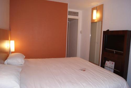 a bedroom with a large white bed and a flat screen tv at Hôtel Ibis Nevers in Nevers