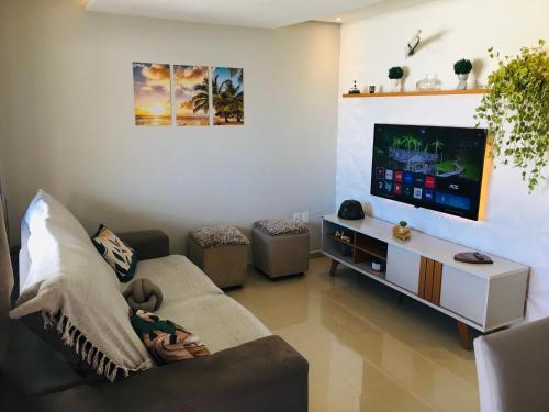 a living room with a person sitting on a couch watching tv at Casa moderna de praia em Itaipuaçu RJ in Maricá