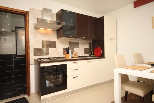a kitchen with a stove top oven next to a table at Apartments with a parking space Valbandon, Fazana - 2214 in Fondole
