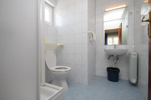 a white bathroom with a toilet and a sink at Double Room Peroj 2235c in Peroj