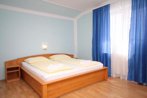 a bedroom with a bed and a window with blue curtains at Triple Room Peroj 2235f in Peroj