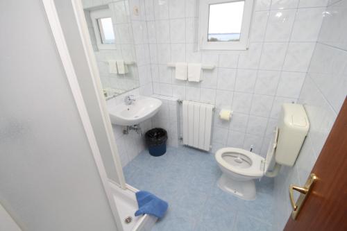 a white bathroom with a toilet and a sink at Double Room Peroj 2235h in Peroj