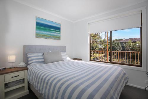 a bedroom with a bed and a large window at Barralong Beach House in Hawks Nest