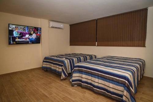 two beds in a room with a tv on the wall at habitacion, tipo hotel 4 personas aire acond, independiente, nuevo TV smart 60 pulgadas D9 in Ciudad Valles