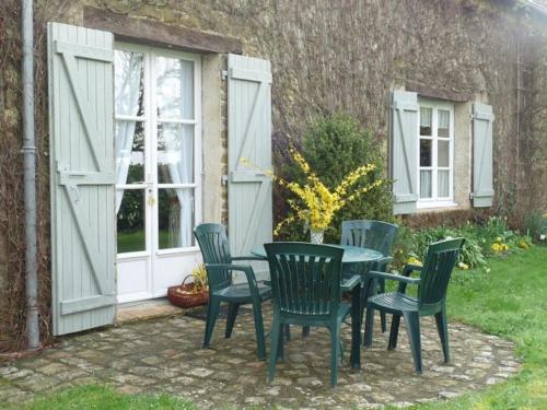 une table et des chaises devant une maison dans l'établissement Gîte charmant avec cheminée, jardin privé et 3 chambres dans un ancien corps de ferme - FR-1-410-128, à Joué-lʼAbbé