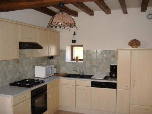 une cuisine avec des armoires blanches, un évier et un micro-ondes dans l'établissement Ancien corps de ferme restauré avec jardin clos, proche A11, 3 chambres, barbecue, calme garanti - FR-1-410-343, à Le Bailleul