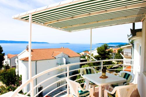 balcón con mesa, sillas y vistas al océano en Apartments Niko, en Trogir