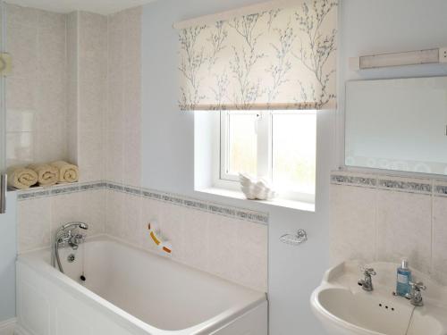 a bathroom with a tub and a sink and a window at The Tides - E5327 in West Bay