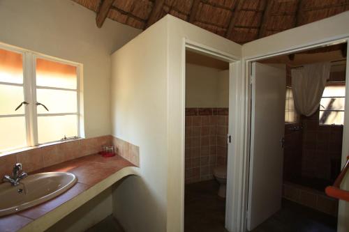 La salle de bains est pourvue d'un lavabo et de toilettes. dans l'établissement Hlane Royal National Park, à Simunye