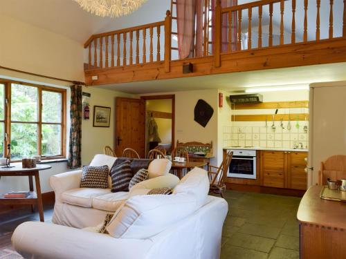 a living room with two white couches and a kitchen at Ty Bach in Cilgwm