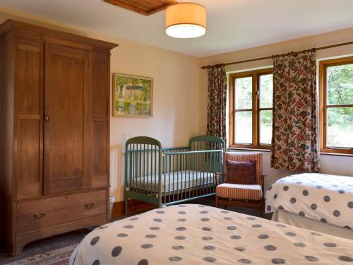a bedroom with two beds and a cabinet and a crib at Ty Bach in Cilgwm