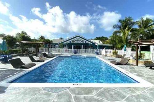 a swimming pool with chairs and a house at Beautiful Villa just steps away from the beach! in Georgetown