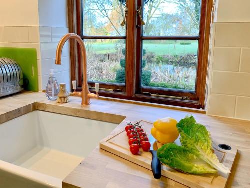 a kitchen counter with vegetables on a cutting board at Moorhen Cottage in Hollingbourne