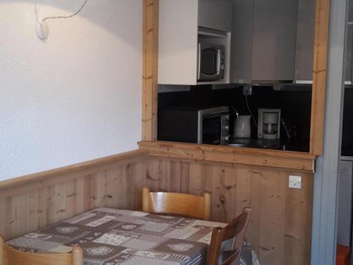 - une cuisine avec une table et un four micro-ondes dans l'établissement Appartement Skis aux Pieds, 4 Personnes, Balcon, Wifi Gratuit, Proche Commerces et Activités - FR-1-574-39, aux Menuires