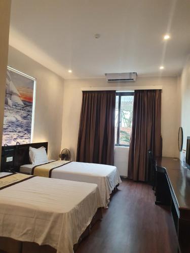 a hotel room with two beds and a window at Khách sạn Đại Dương Diễn Châu - Nghệ An in Diễn Châu
