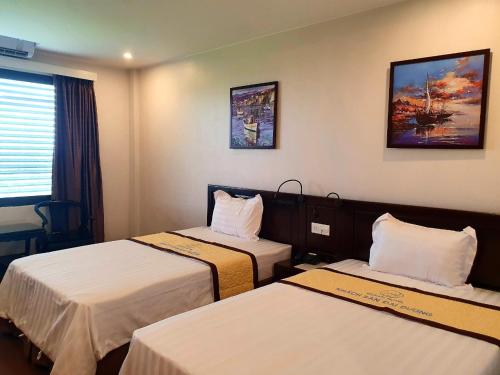 a hotel room with two beds and a painting on the wall at Khách sạn Đại Dương Diễn Châu - Nghệ An in Diễn Châu