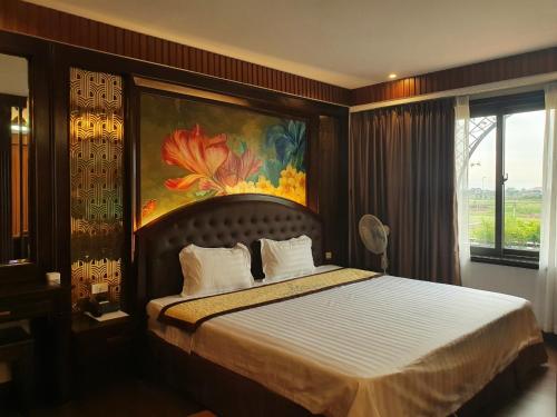 a bedroom with a bed with a painting on the wall at Đại Dương - Ocean Hotel in Diễn Châu