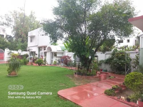 a yard in front of a house with a tree at Green Serene Abode in Meerut