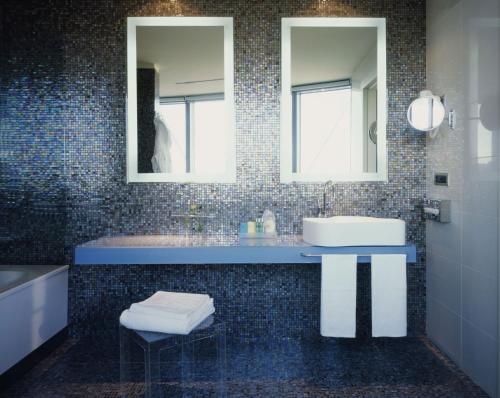 a bathroom with a sink and two mirrors at UNA HOTELS T Hotel Cagliari in Cagliari