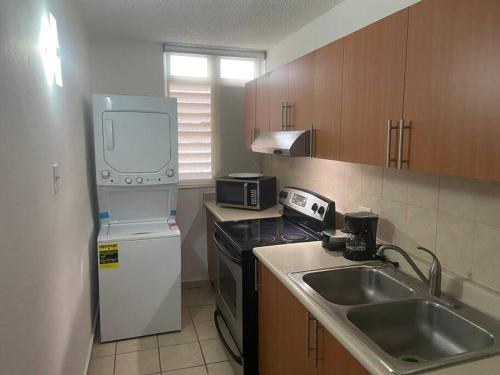 una pequeña cocina con fregadero y nevera. en cozy private apartment near sju airport, en Carolina